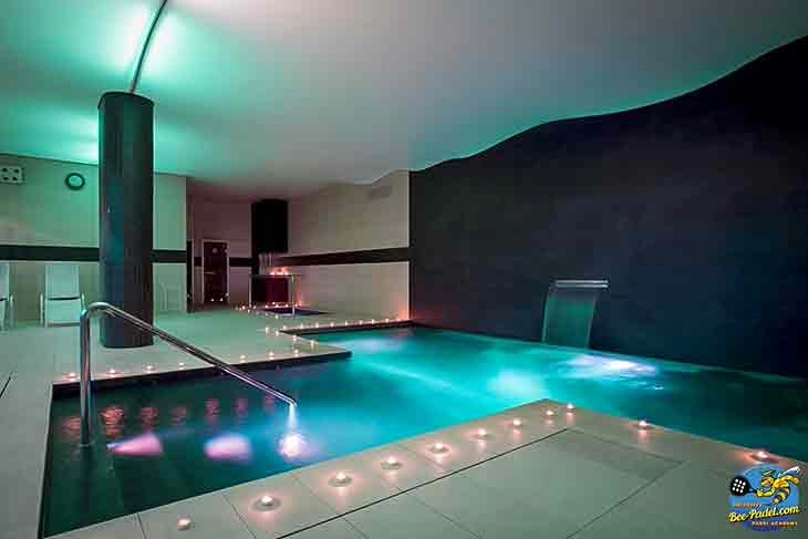 Indoor pool at URH Hotel Mataró with sauna visible in the background, offering relaxation for padel retreat guests.