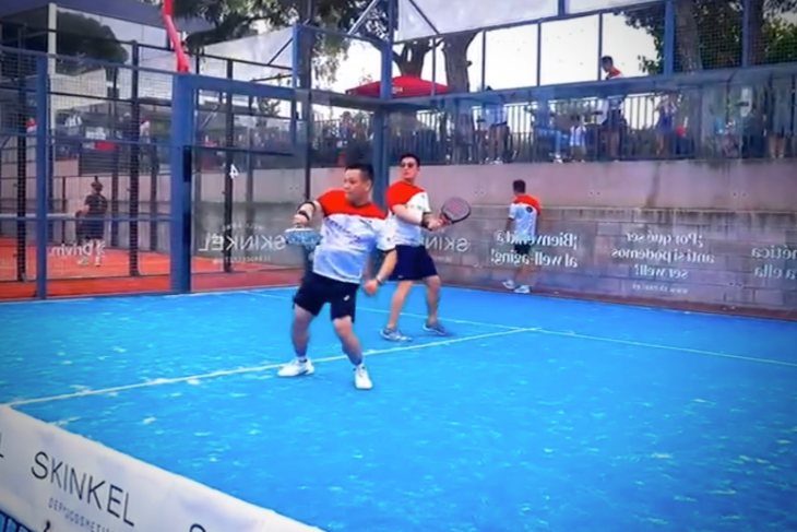 Padel players smiling and cooperating during an intense rally at Can Teixidó Padel Club, showing teamwork and energy on the panoramic courts.