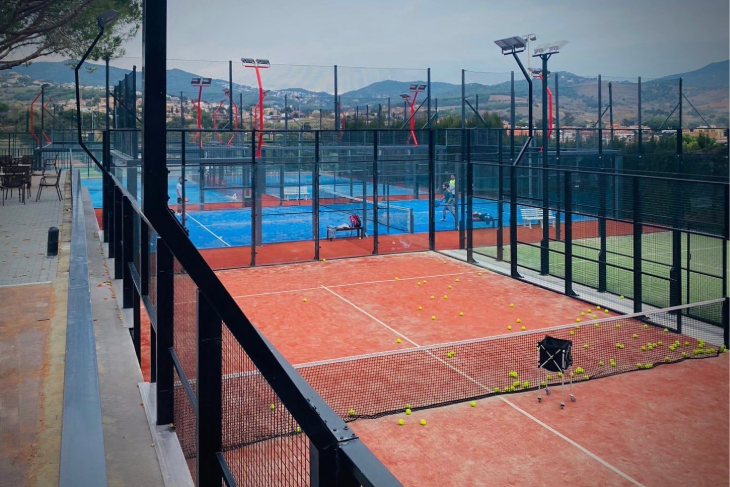 View from the terrace bar at Can Teixidó Padel Club, overlooking the panoramic padel courts with players training and competing.
