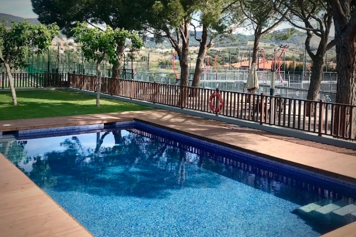 Player enjoying a refreshing swim in the outdoor pool at Can Teixidó Padel Club after an intense padel training session.